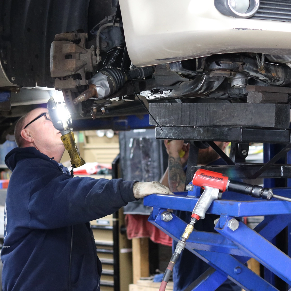 Technician performing oil change and under-hood maintenance