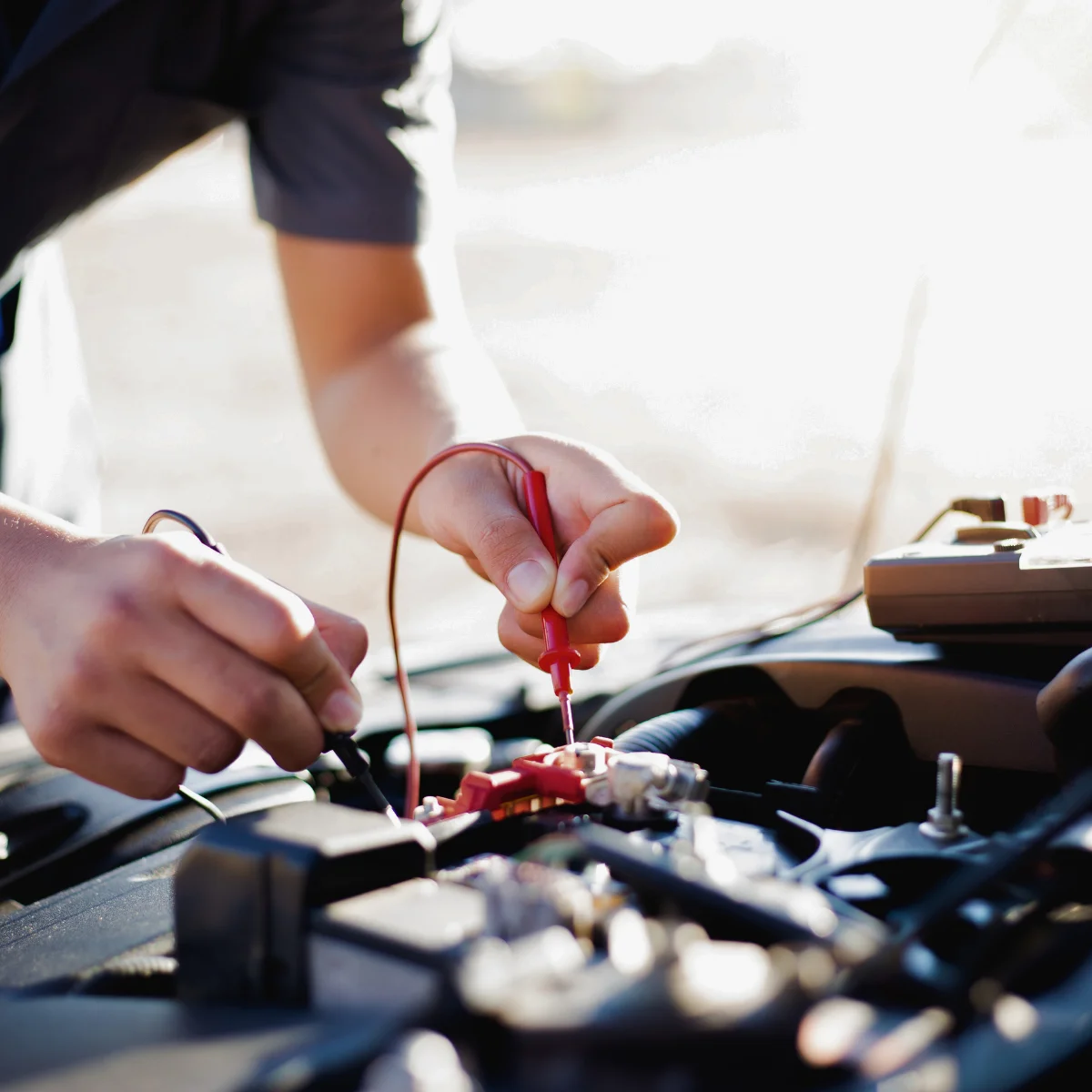 Technician testing car battery and electrical connections