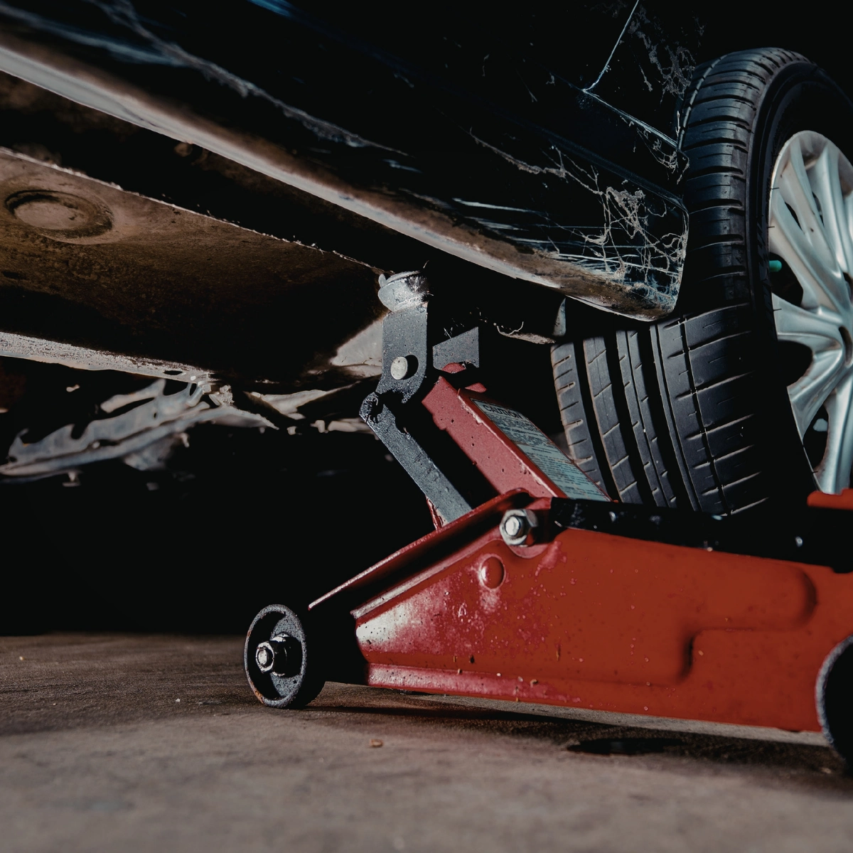 Mechanic inspecting vehicle suspension and exhaust
